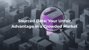 Illustration of a magnifying glass highlighting a single purple building among a dense, grey cityscape, symbolizing the power of sourced data to stand out in a crowded market. Text overlay reads: 'Sourced Data: Your Unfair Advantage in a Crowded Market'.